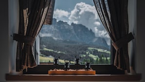 Una ventana con cortinas, un estante de madera y tres figuritas de ciervo.
