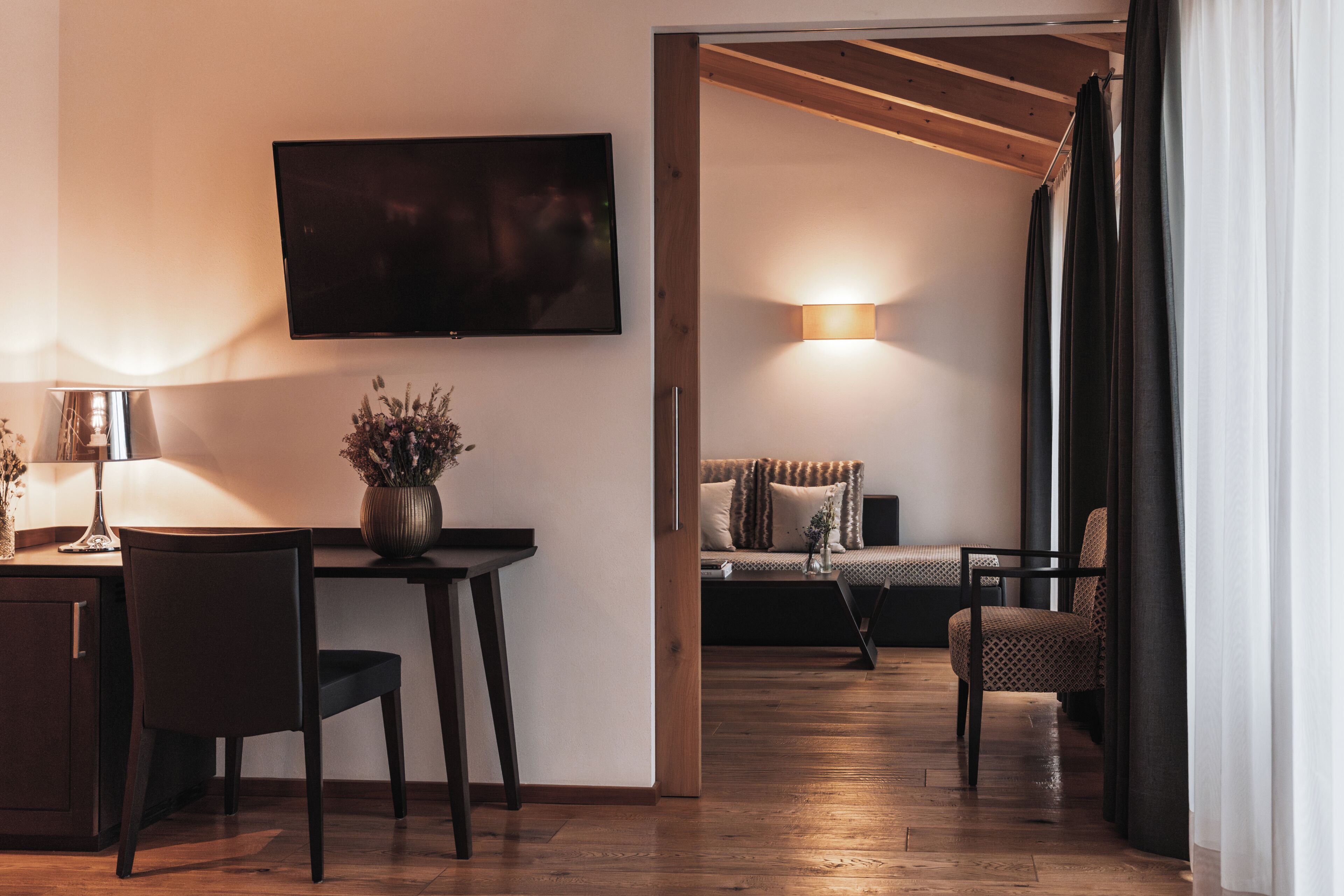 Een moderne woonkamer met een flatscreen televisie, een eethoek met een tafel en stoelen, en een zithoek.