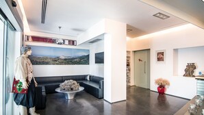 A modern interior with a seating area, a large painting, and a red vase with dried flowers. - Nefeli Villas (Skiros)