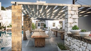 An outdoor patio with a wooden table and chairs, stone walls, and potted plants. - Nefeli Villas (Skiros)