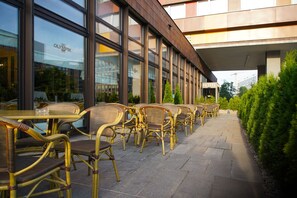 A hotel exterior with outdoor seating and large windows. - Hotel Olympik (Prague)