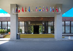 The entrance of the Hotel Olympik with multiple flags displayed above the entrance. - Hotel Olympik (Prague)