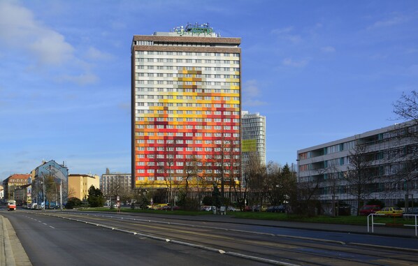 A tall hotel with a modern design, featuring a prominent red and yellow facade. - Hotel Olympik (Prague)