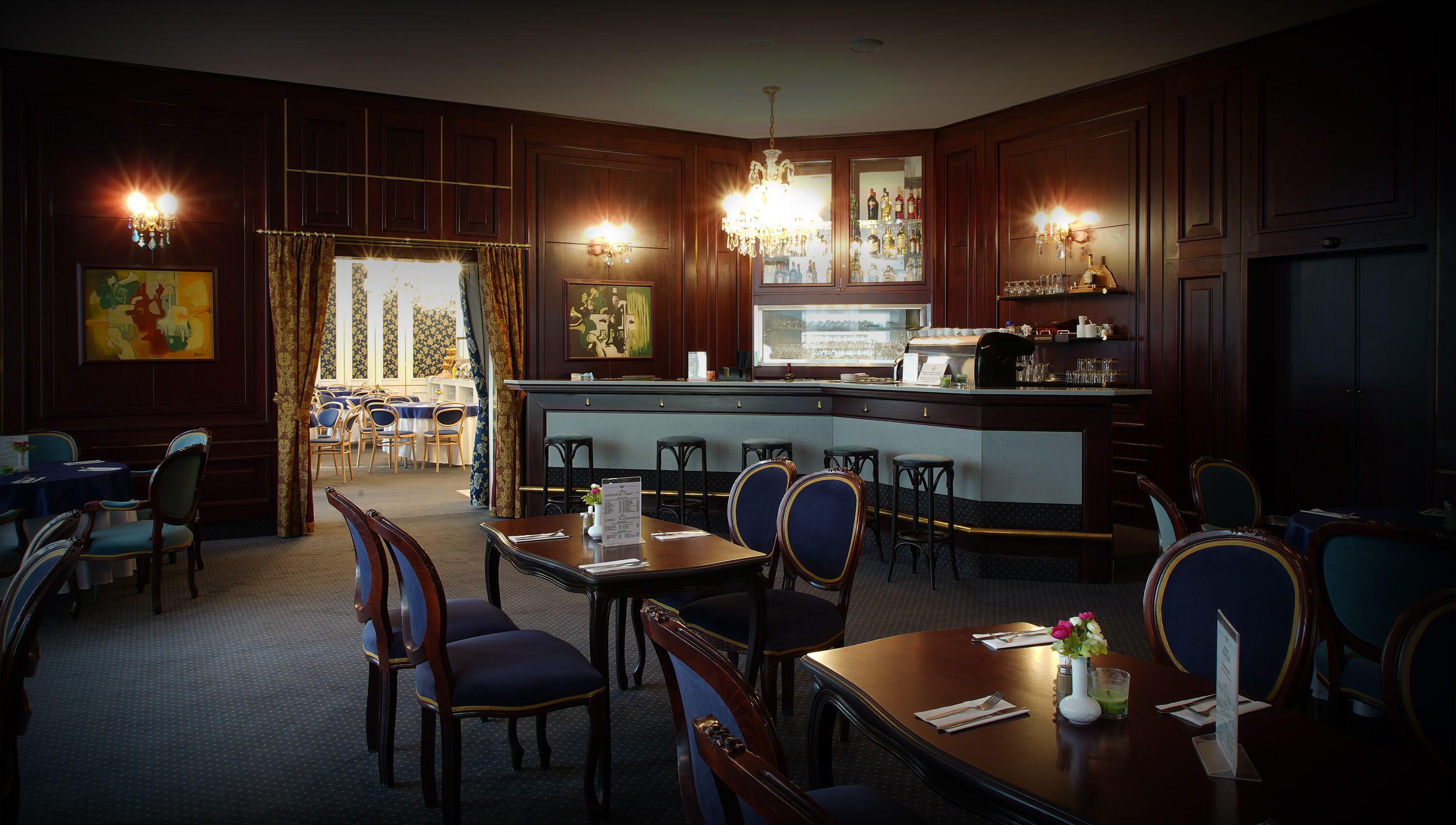 Un restaurante con zona de bar, paneles de madera y candelabros.