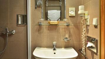 A bathroom with a sink, mirror, towel rack, and a shower head.