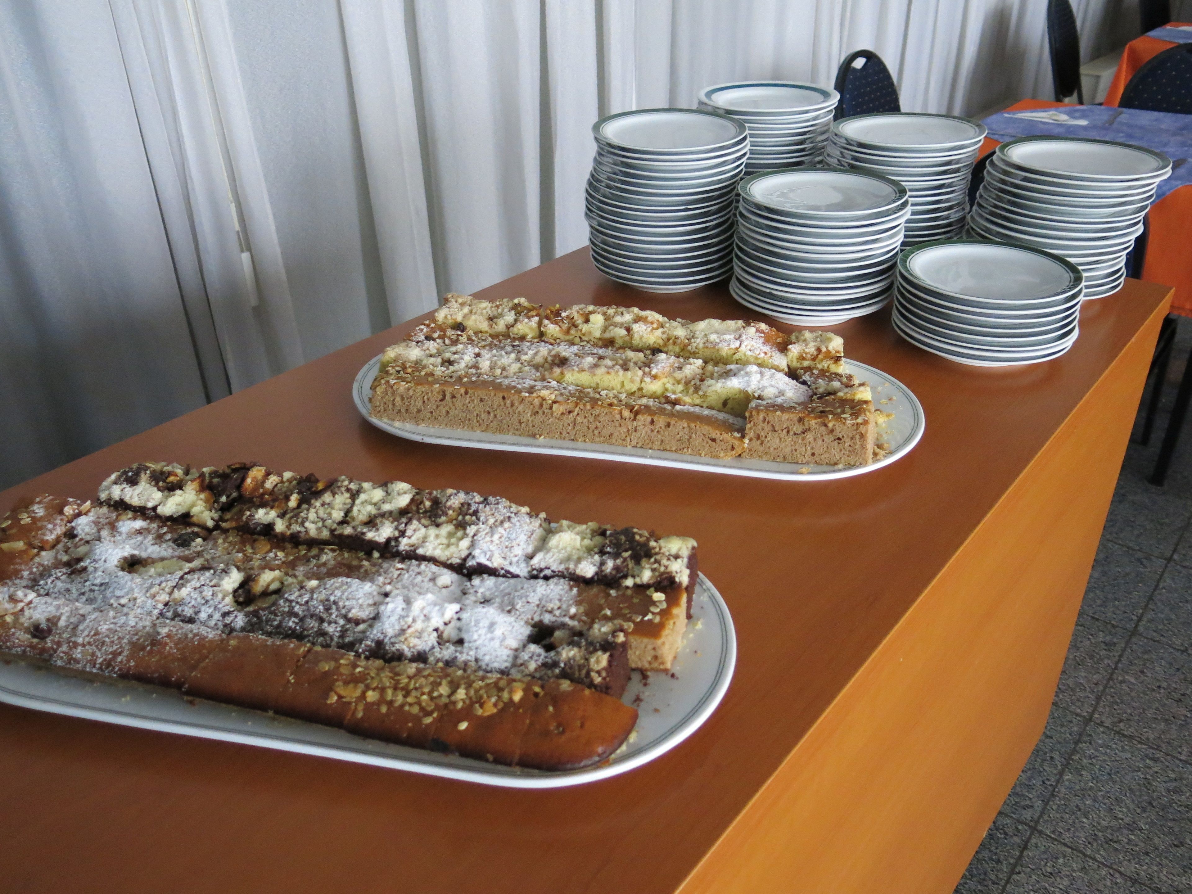 Un tavolo da buffet con due torte grandi e pile di piatti.