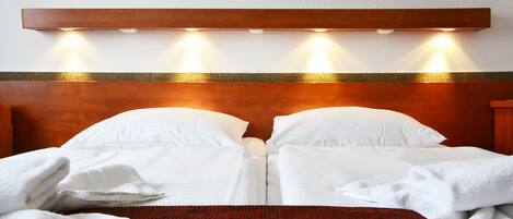 A hotel room with a wooden headboard, two white beds, and a red textured rug.