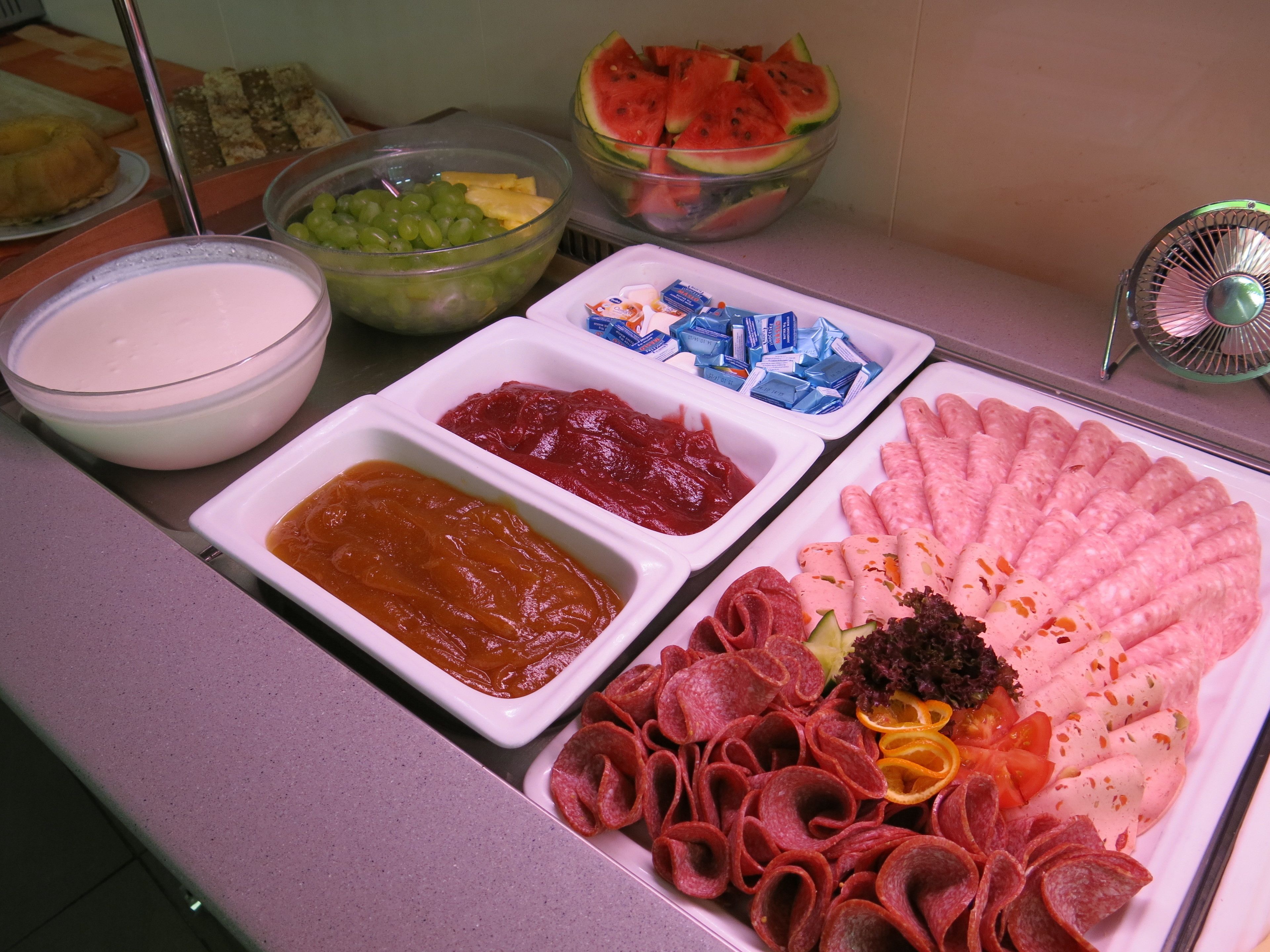 A buffet with various food items including dips, fruits, and meats.