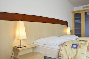 Ein Schlafzimmer mit Bett, Nachttischlampen, einem Holzkopfende und einem Kleiderschrank.