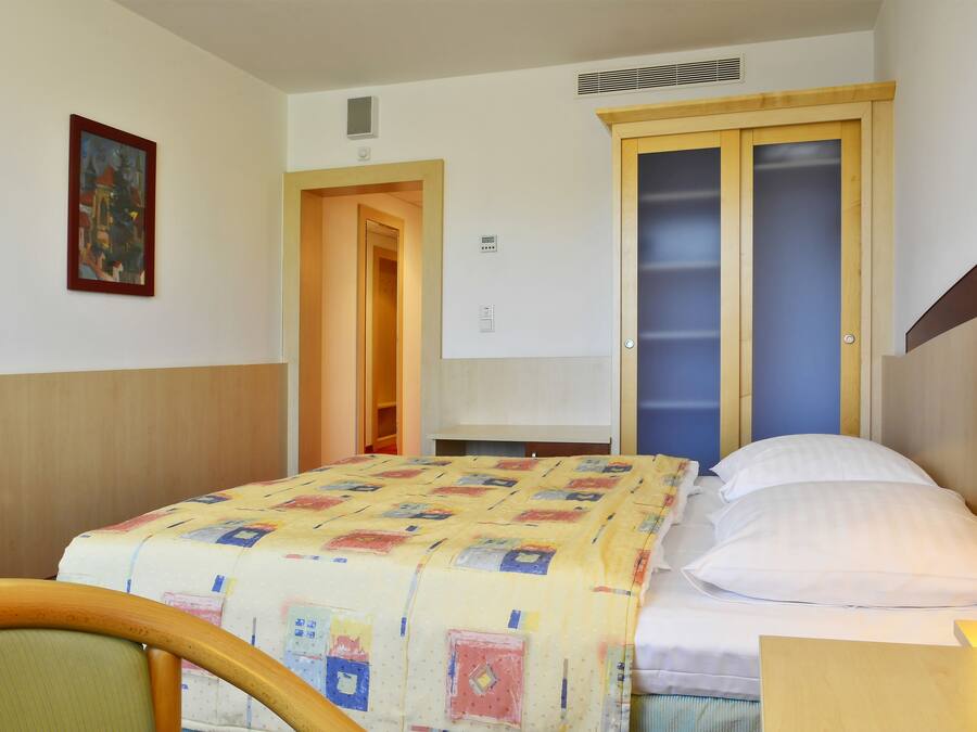 Habitación de hotel con cama, una silla, un escritorio y un cuadro en la pared.