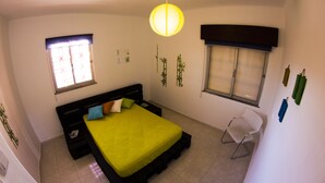 A bedroom with a bed, a chair, and two windows. - Alameda Hostel (Portimão)