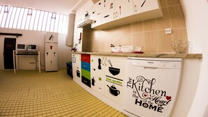 A kitchen with a tiled backsplash, a dishwasher, and various kitchen utensils displayed on the wall. - Alameda Hostel (Portimão)