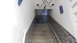 A staircase with patterned tiles, a chandelier, and a clock on the wall. - Alameda Hostel (Portimão)