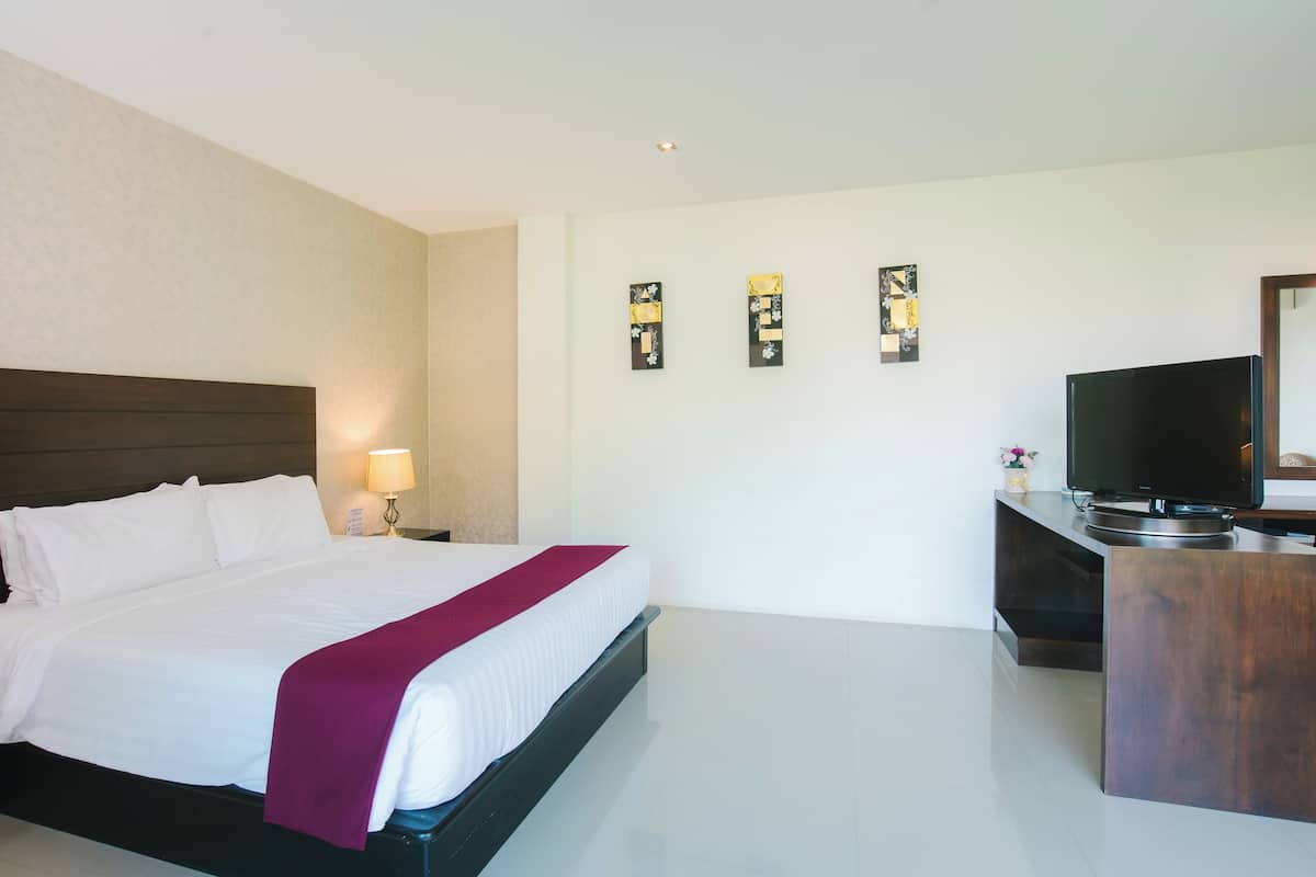 Habitación de hotel con una cama grande, televisión, escritorio y cuadros en la pared.