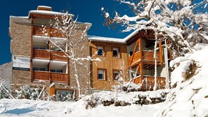 Un hôtel à plusieurs étages, doté d’une façade en pierre et de balcons en bois.