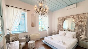 Un dormitorio con una cama grande, una araña, un espejo decorativo y una ventana con cortinas.