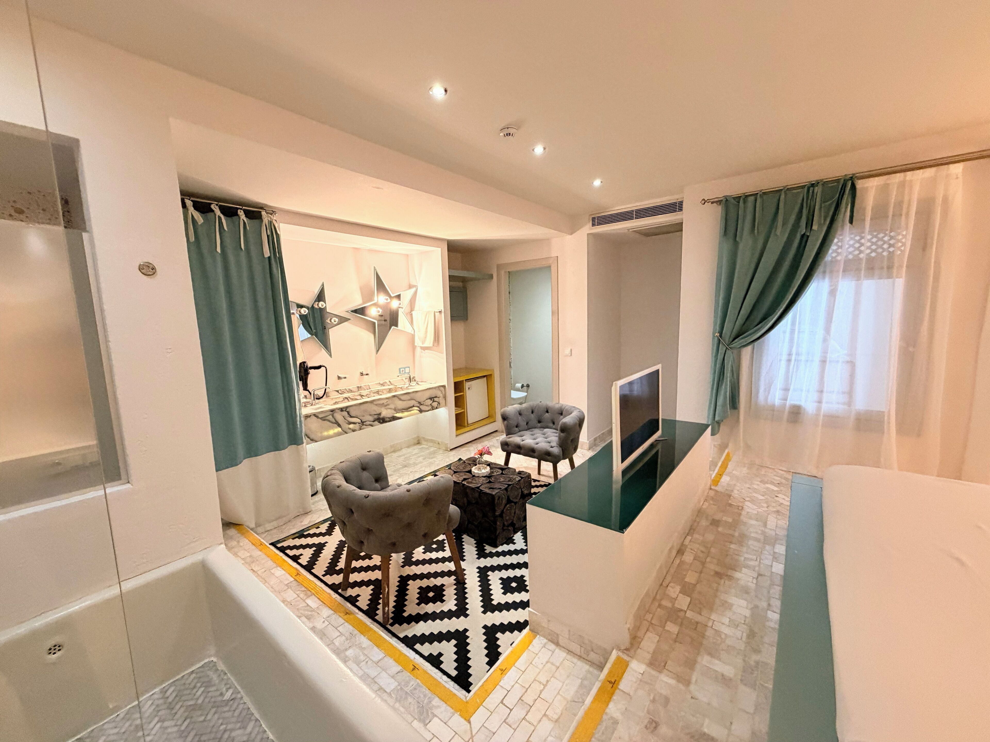 A modern living room with a sofa, a coffee table, a TV, and a patterned rug.