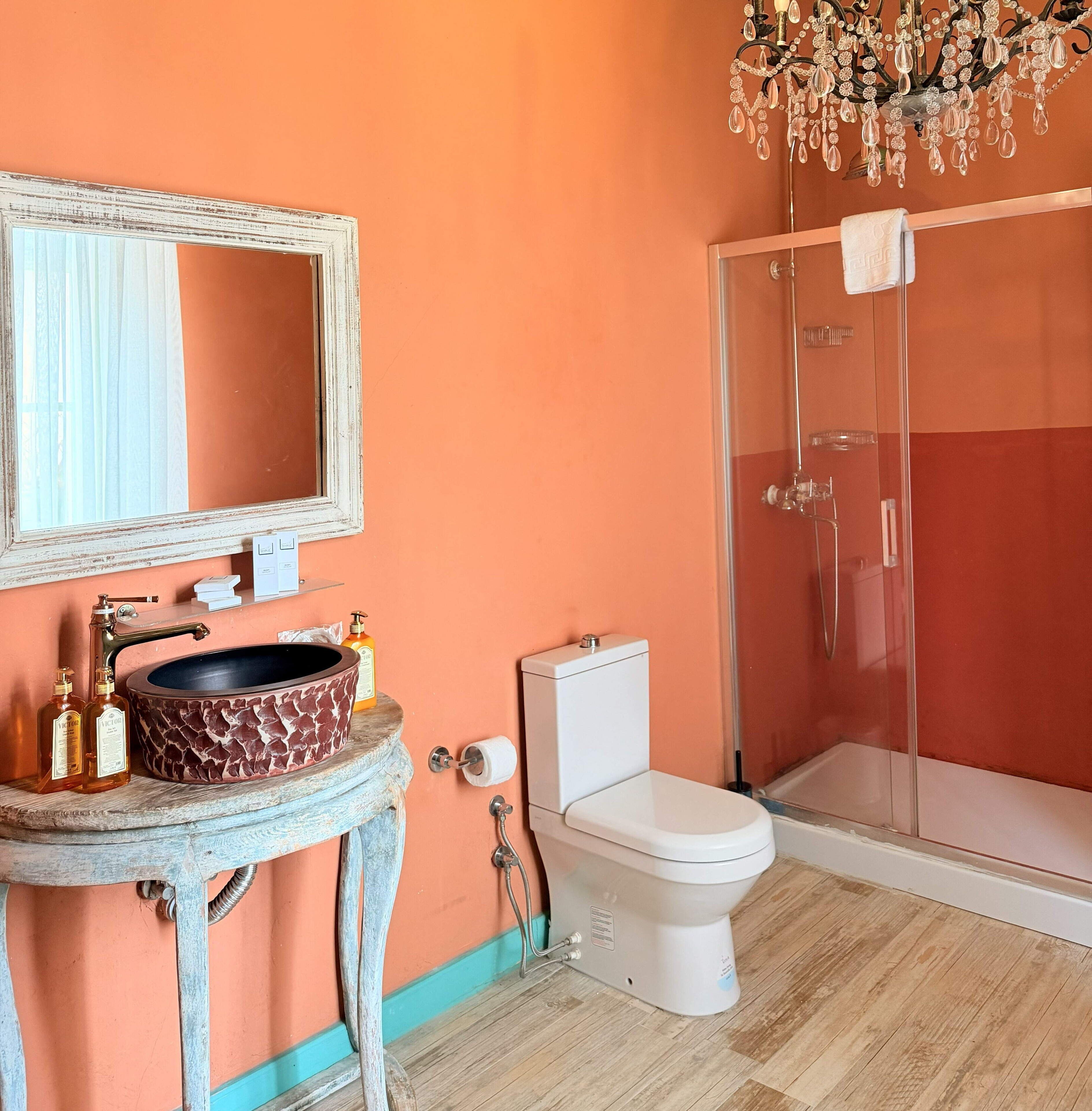 Un baño con un lavabo redondo, un inodoro, una ducha y un espejo.