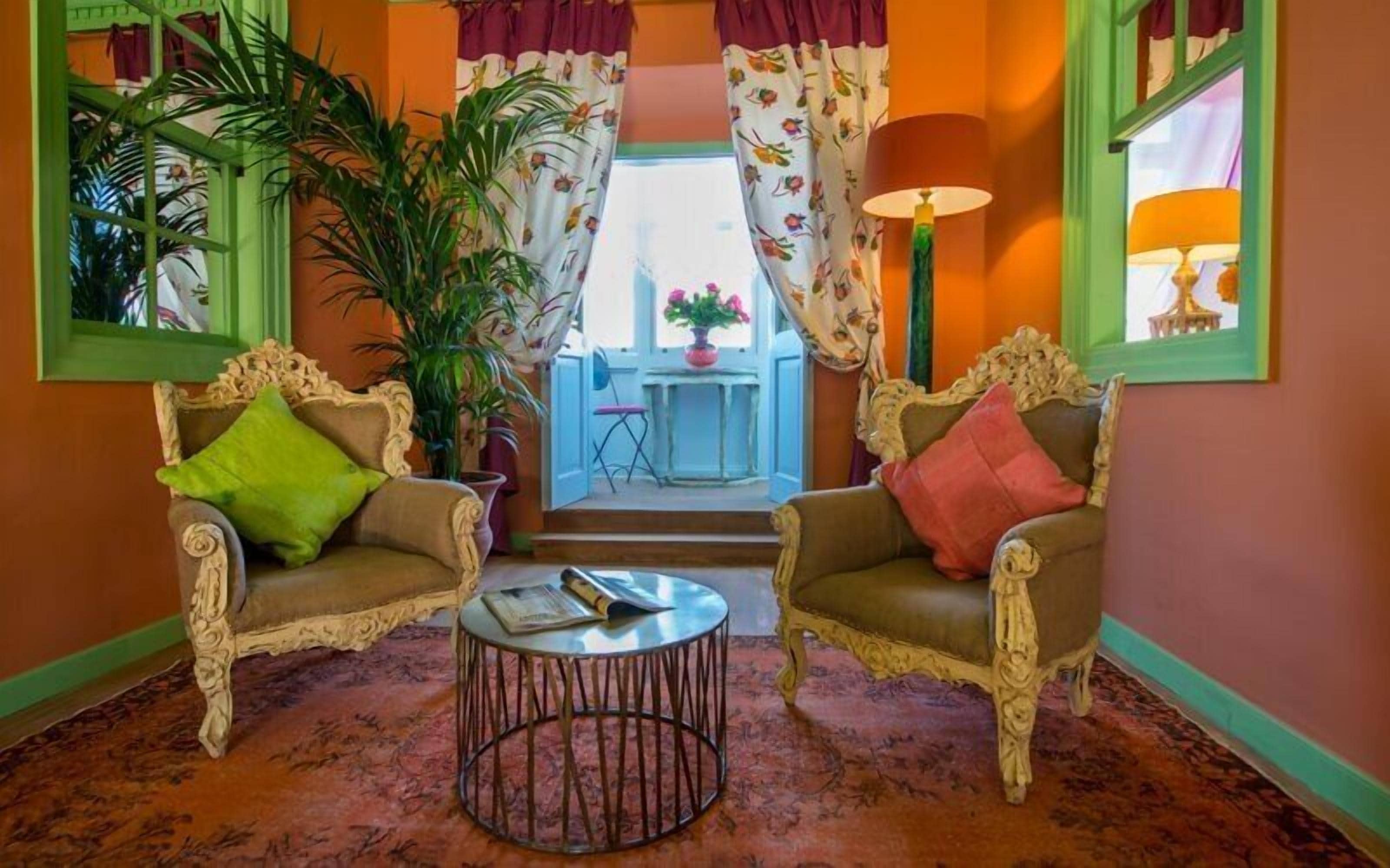 Una habitación con dos sillones decorativos, una mesa de centro redonda y vistas a un balcón con mesa y sillas.