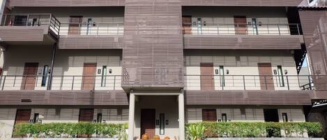 A multi-story building with a flat roof, balconies, and a central entrance.