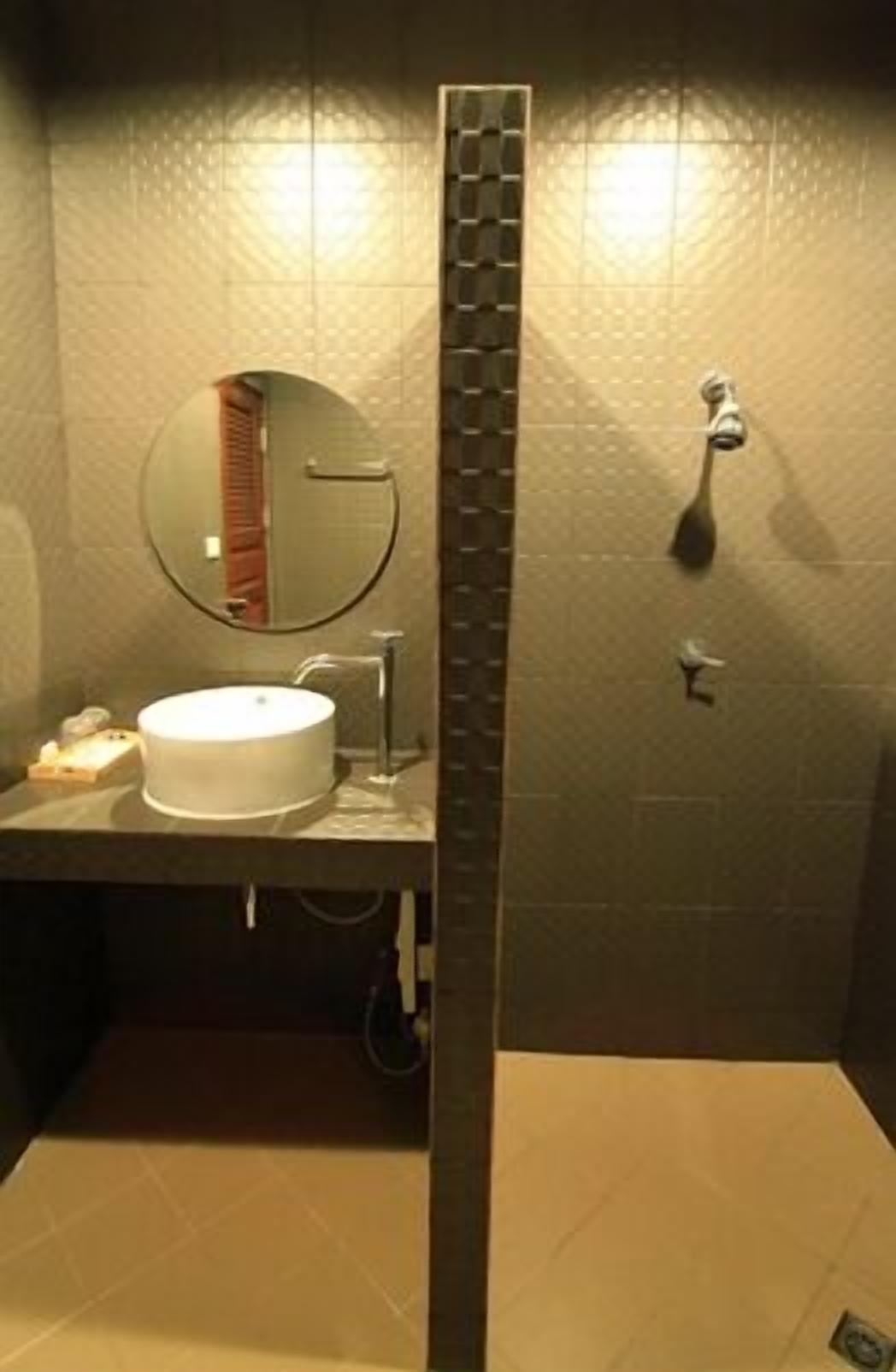 A bathroom with a round mirror, a sink, and a shower area.