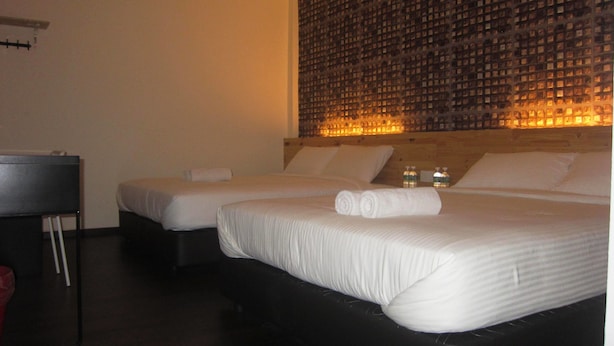 A hotel room with two beds, a wooden headboard, and a wall with a patterned design. - Dream Garden Hotel (Klang)