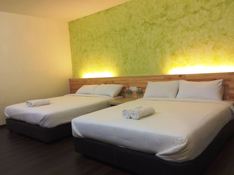 Two single beds with wooden headboards, white linens, and rolled towels.