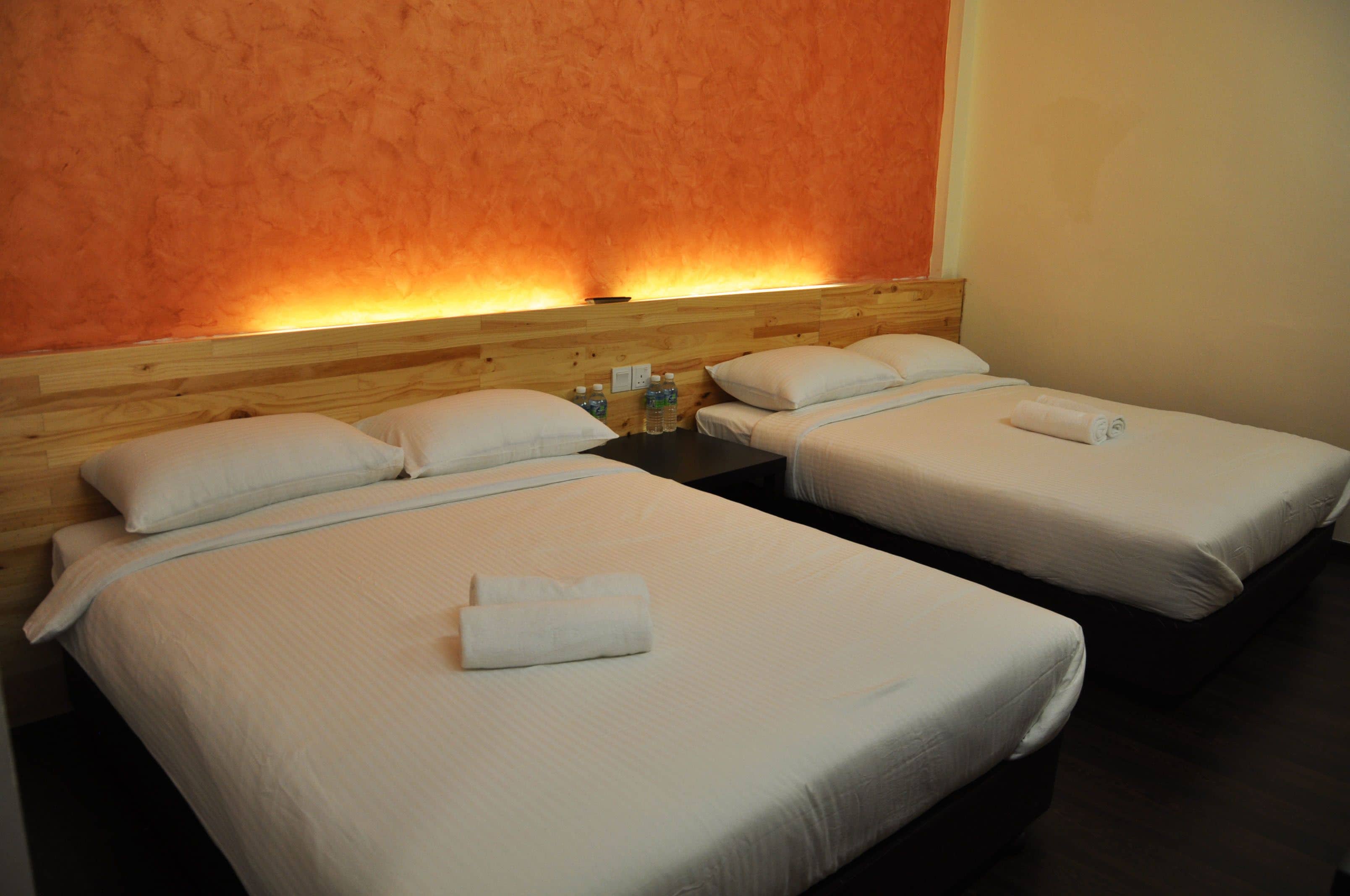 Una habitación de hotel con dos camas individuales, cada una con cabecero de madera, ropa de cama blanca y una toalla enrollada.