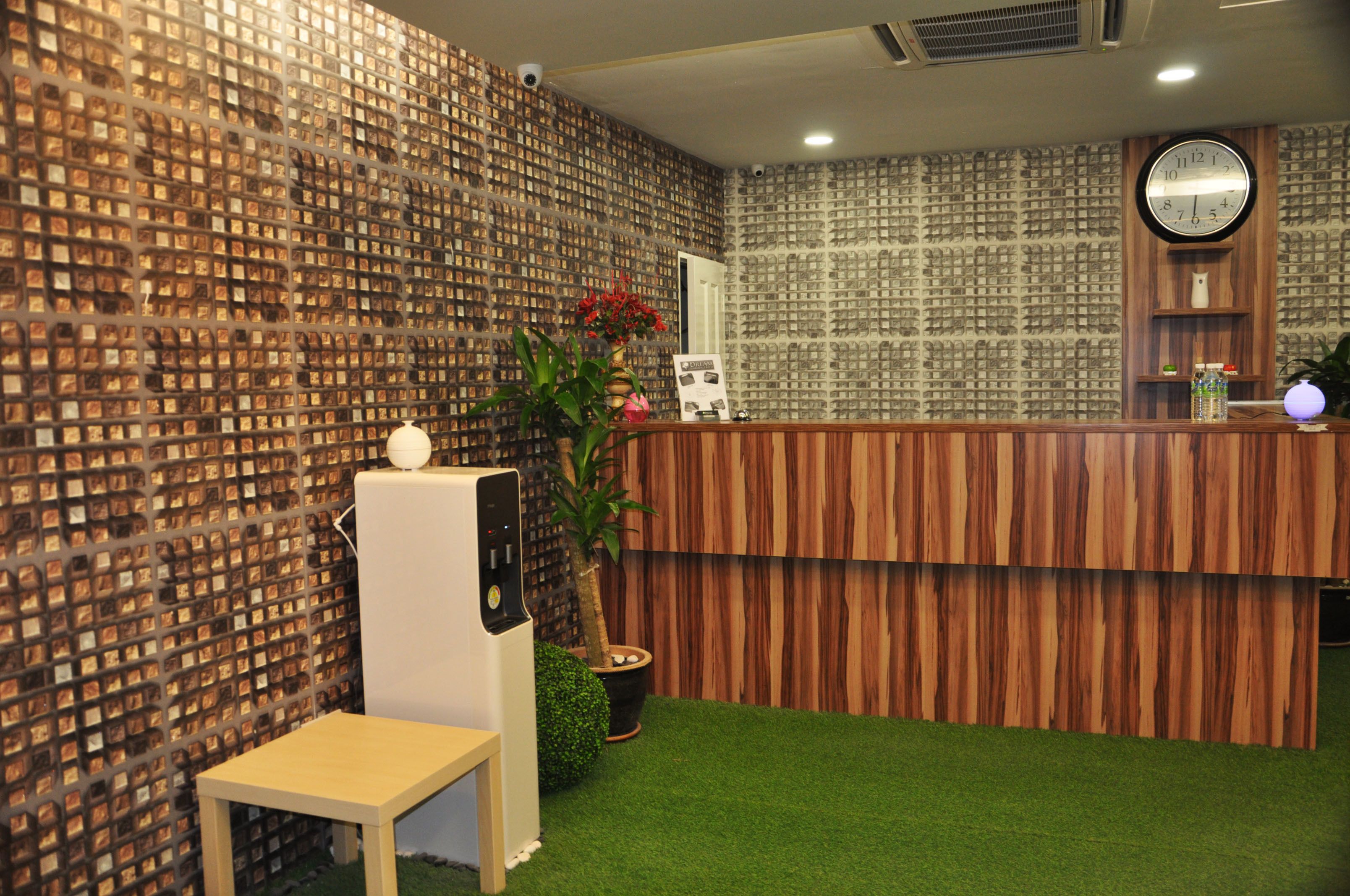 A reception area with a wooden reception desk, a clock, and a wall decorated with numerous small photographs.