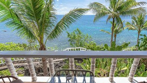 A balcony with a glass table, white balustrade, and a view of the ocean. - Blue Star Dive & Resort (Anda)