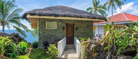 A stone building with a thatched roof, a wooden door, and a small porch.