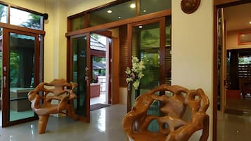 A modern interior with glass doors leading to an outdoor area, a wooden sculpture, and a vase with flowers.