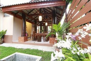 A covered outdoor seating area with a table and chairs, surrounded by potted plants and flowers. - Baanmalai Hotel Chiangrai (Chiang Rai)