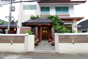 A two-story house with a tiled roof, a wooden porch, and a brick wall. - Baanmalai Hotel Chiangrai (Chiang Rai)