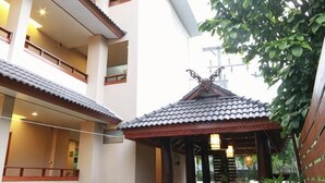 A traditional-style building with a tiled roof, a wooden structure with a decorative roof, and a balcony. - Baanmalai Hotel Chiangrai (Chiang Rai)
