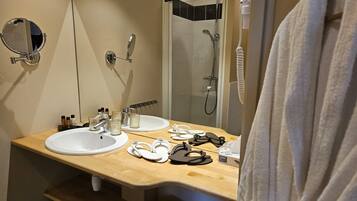 Un baño con dos lavamanos, un espejo, una ducha y una bata colgada en la puerta.