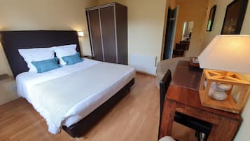 Una habitación de hotel con una cama grande, un armario, un escritorio con lámpara y una silla.