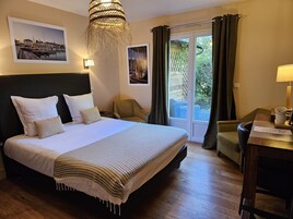 Habitación de hotel con una cama grande, una silla, un escritorio y vistas al exterior.