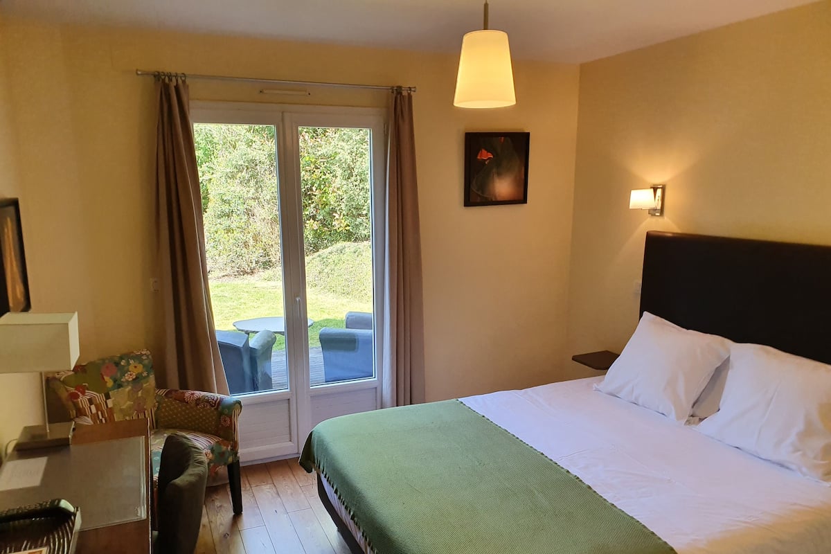 A hotel room with a bed, a desk, a chair, and a window with curtains.