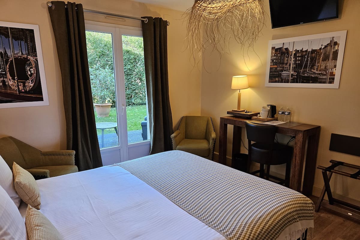 A hotel room with a large bed, a desk with a chair, a television, and a window with curtains.