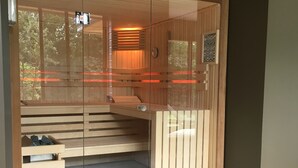 A modern sauna with a glass door, wooden benches, and a tiled floor. - La Fraîchette (La Riviere-Saint-Sauveur)