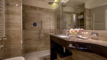 A modern bathroom with a glass-enclosed shower, a marble vanity, and a large mirror.