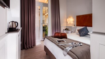 A hotel room with a bed, a bedside table with a lamp, a telephone, and a brown leather bag on the bed.