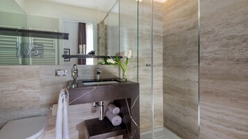 Un baño moderno con ducha de vidrio, lavamanos de mármol y un inodoro.