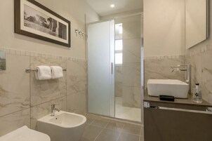 A modern bathroom with a bidet, a sink, and a glass shower enclosure.