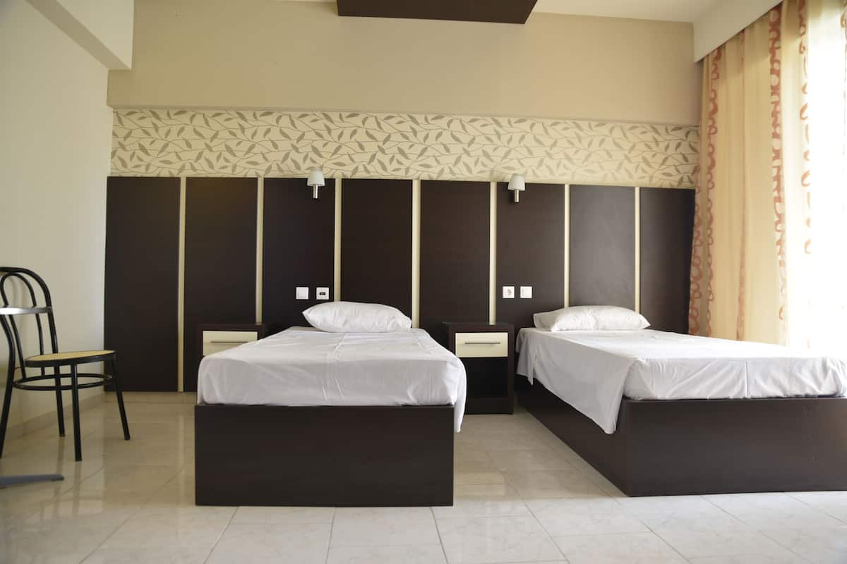 Ein Hotelzimmer mit zwei Betten, einem Sessel und einer Wand mit Muster.