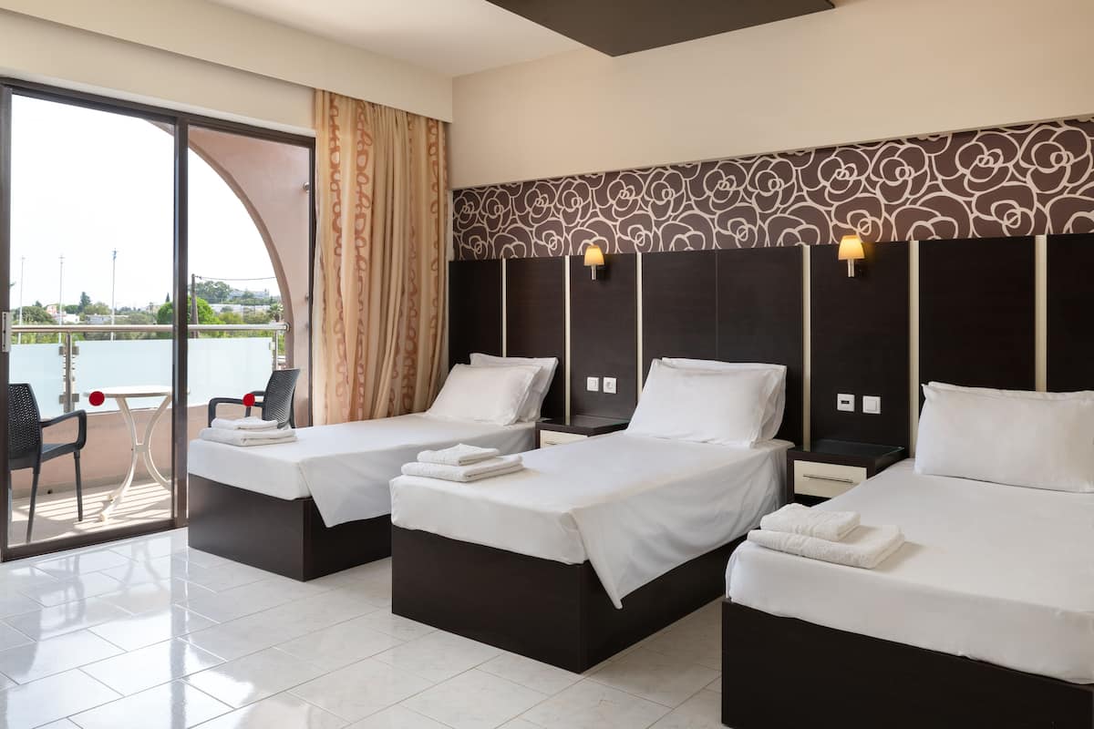 Ein Hotelzimmer mit zwei Betten, einem Balkon mit Tisch und Stühlen und Blick auf das Meer.