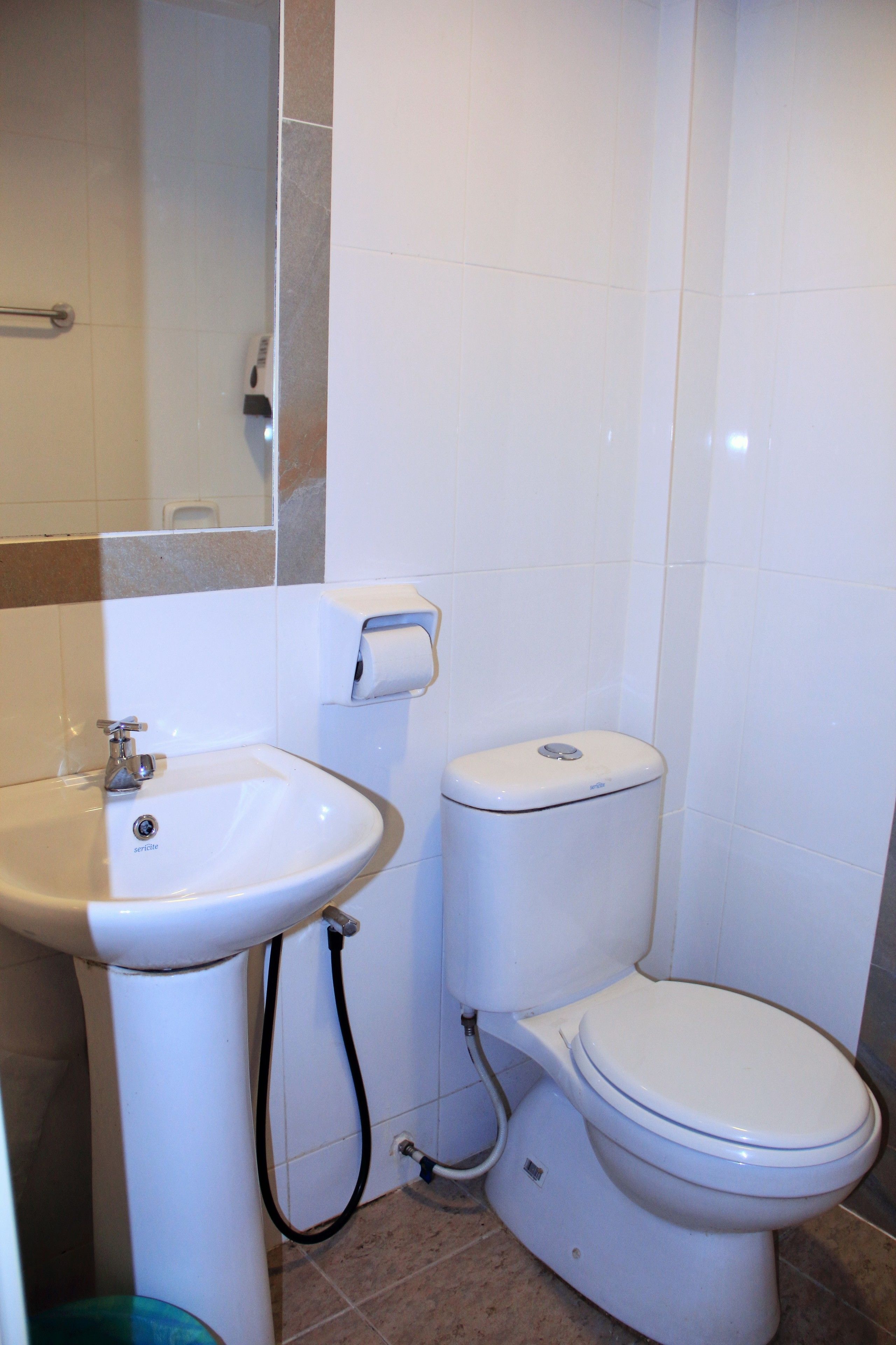 Un baño con lavamanos, inodoro y espejo.
