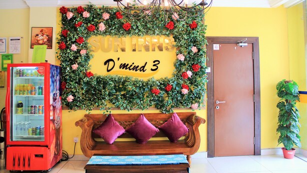 A reception area with a red vending machine, a wooden bench with purple cushions, a chandelier, and a door. - Sun Inns D'mind 3 Seri Kembangan (Seri Kembangan)