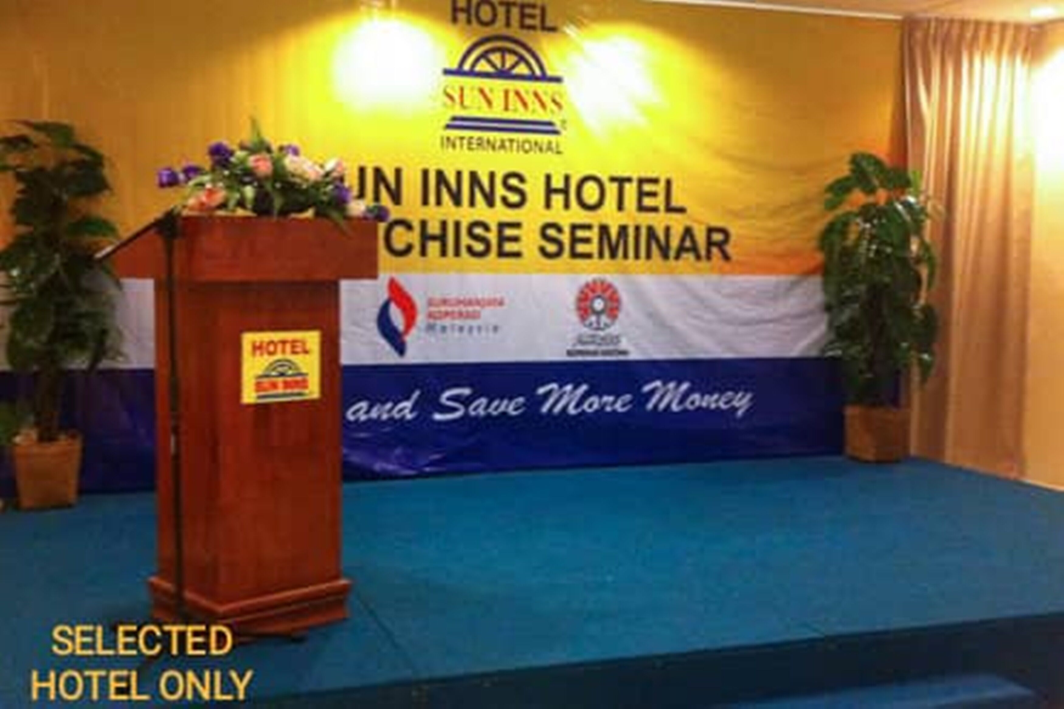 A stage with a podium labeled "HOTEL" and a banner reading "SUN INNS HOTEL CHISE SEMINAR".